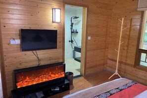 A wooden room with a fireplace, a television, a shower, and a bed. - Heizhugou Midou Hotel (Ebian)