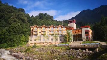 Un hotel de varios pisos, con una entrada destacada y vista al río.