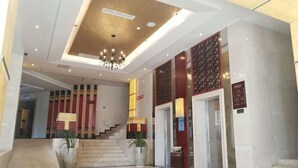 A hotel lobby with a staircase, a chandelier, and a reception desk. - Heizhugou Midou Hotel (Ebian)
