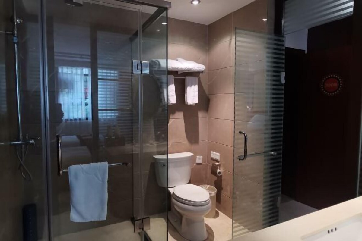 A modern bathroom with a glass-enclosed shower, a toilet, and a sink.