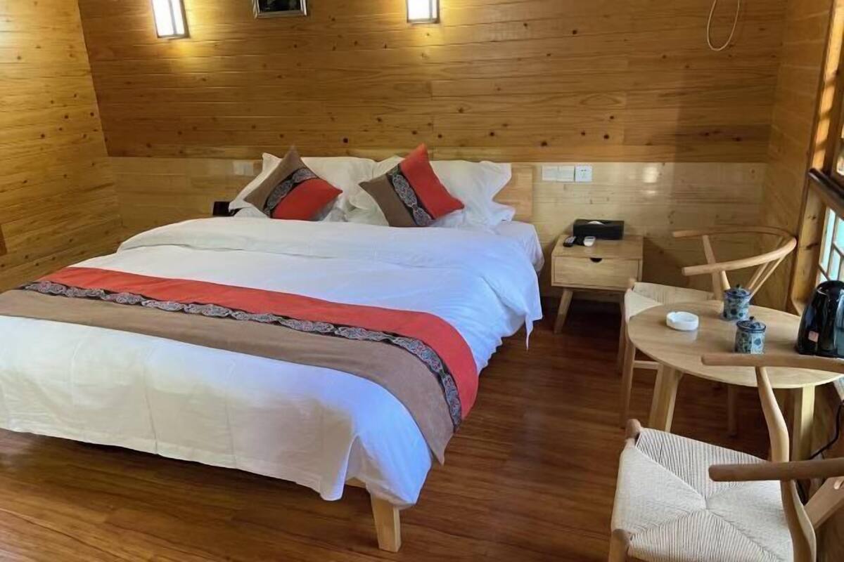 A wooden cabin bedroom with a bed, bedside table, and a small round table with chairs.