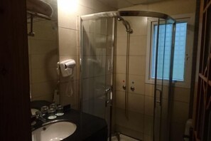 A bathroom with a glass-enclosed shower, a sink, and a mirror. - Heizhugou Midou Hotel (Ebian)