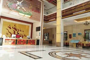 A hotel lobby with a reception desk, a large wall mural, and a patterned floor. - Heizhugou Midou Hotel (Ebian)
