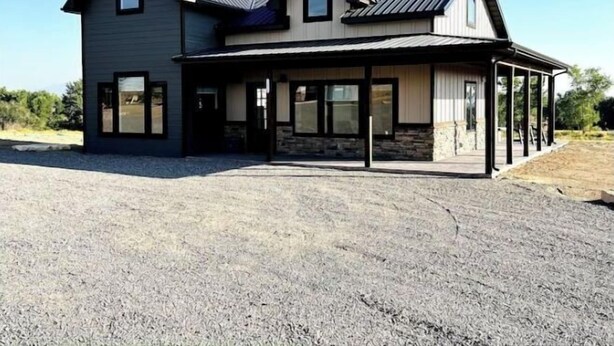 Een tweelaags huis met een grote garage en een overdekte veranda.