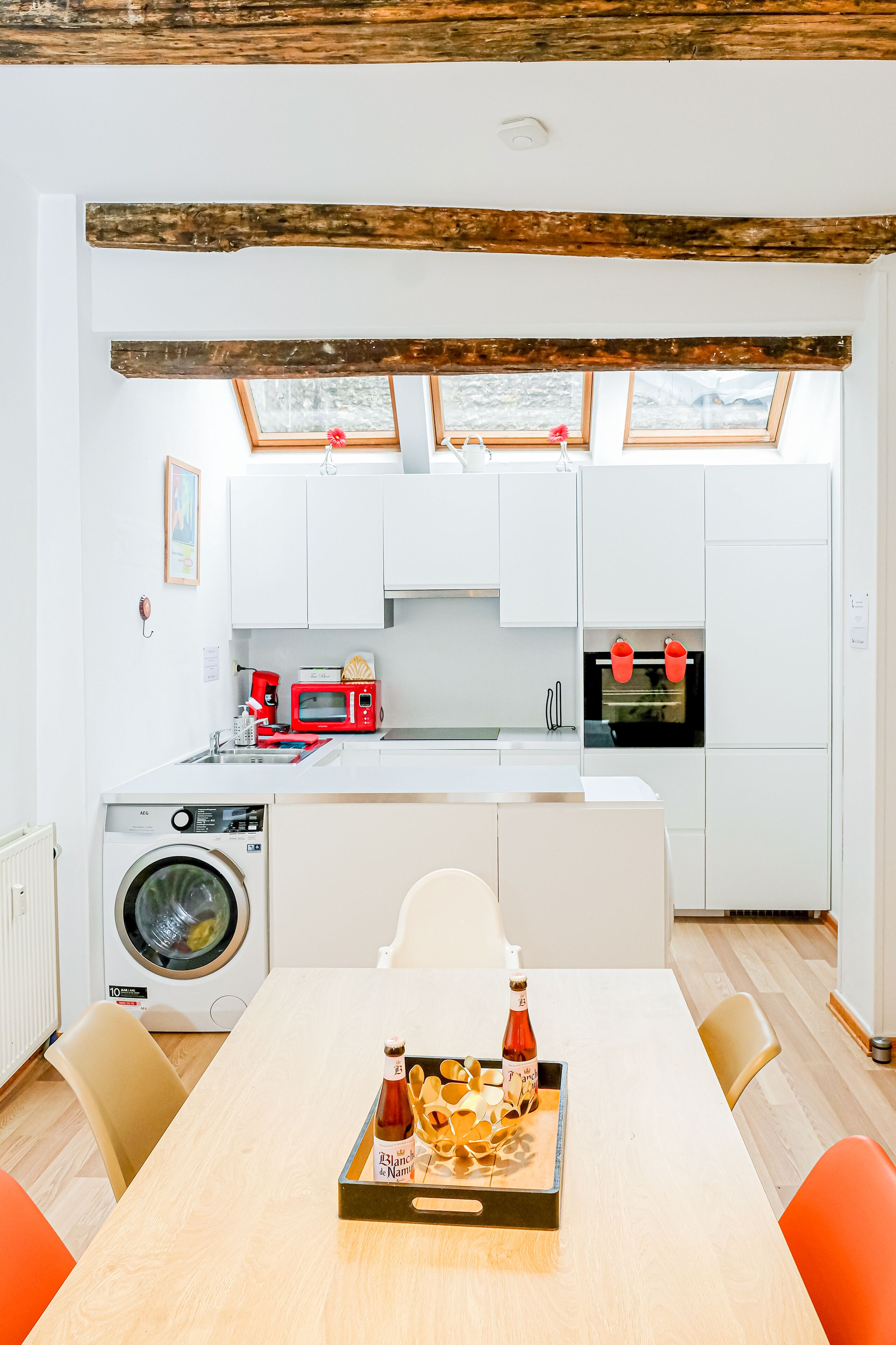 A modern kitchen with white cabinets, a red microwave, and a washing machine.