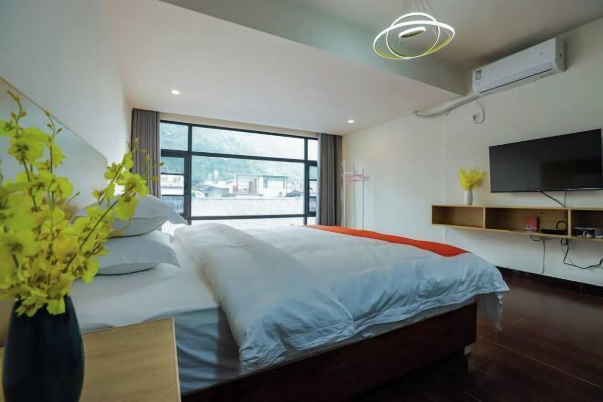 Une chambre d’hôtel moderne avec un grand lit, une télévision et une fenêtre donnant sur la ville.