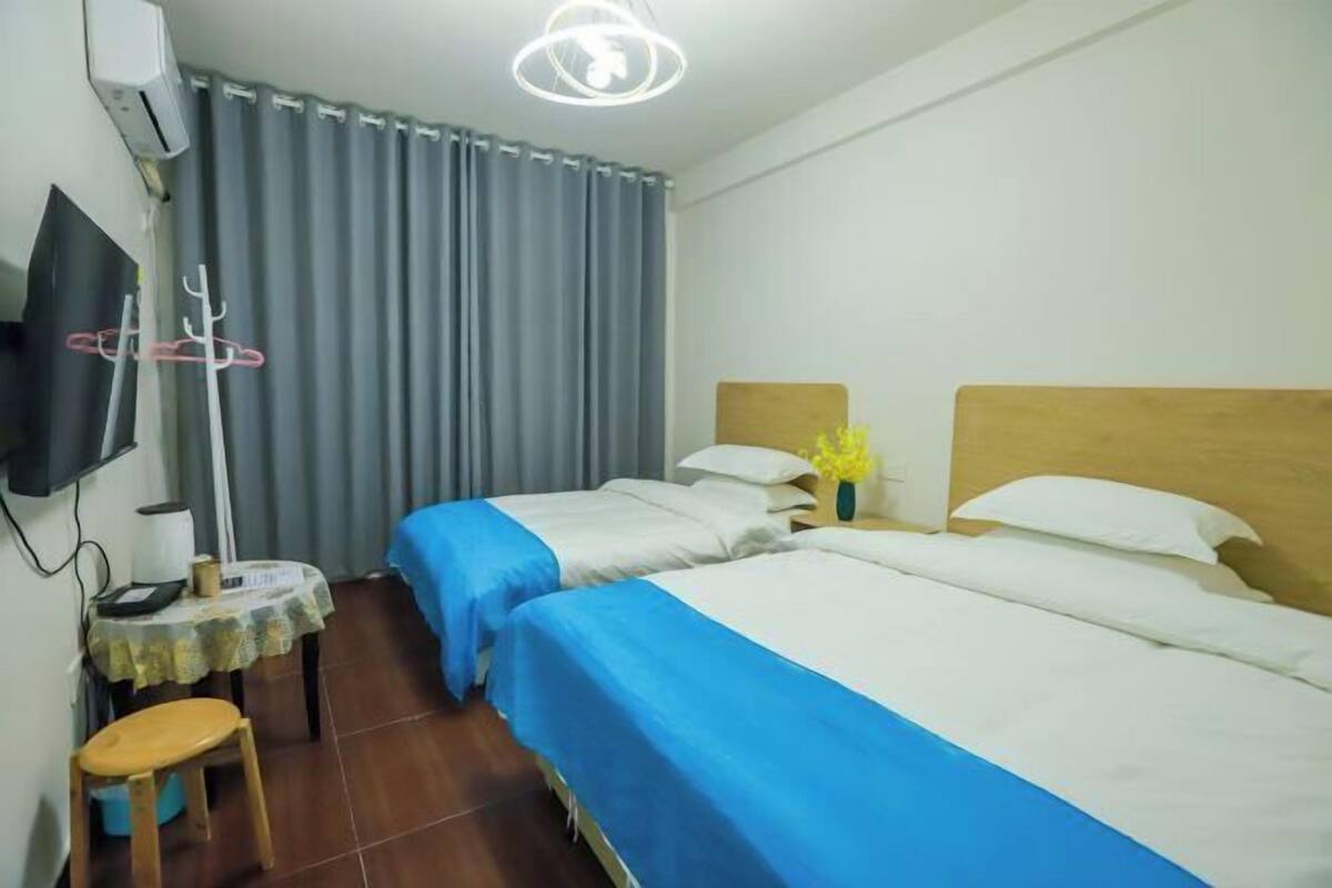 Une chambre d’hôtel avec deux lits, une télévision, une table avec une chaise et un porte-manteau.