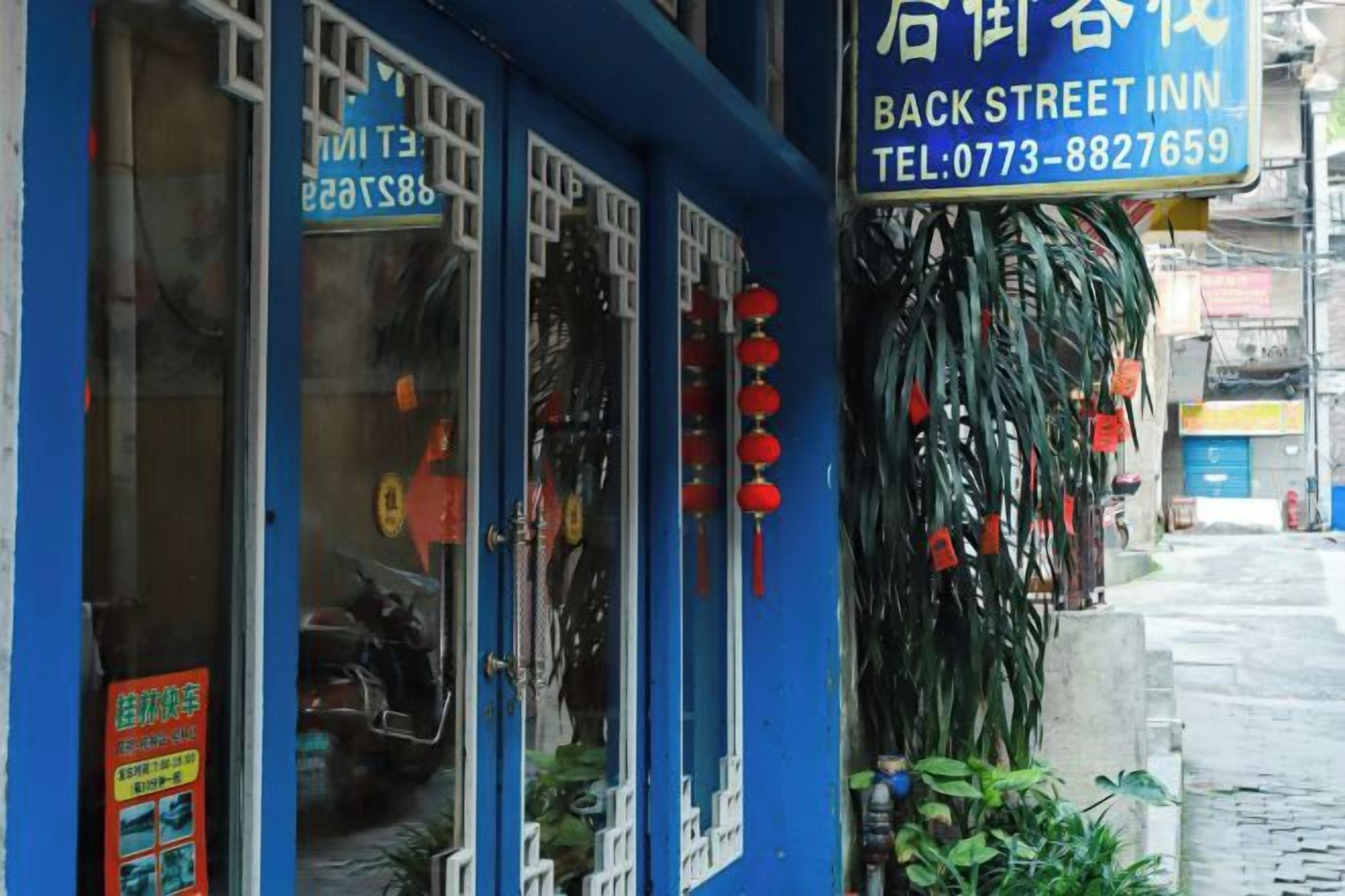 A blue building with a sign for 'BACK STREET INN' and a contact number.