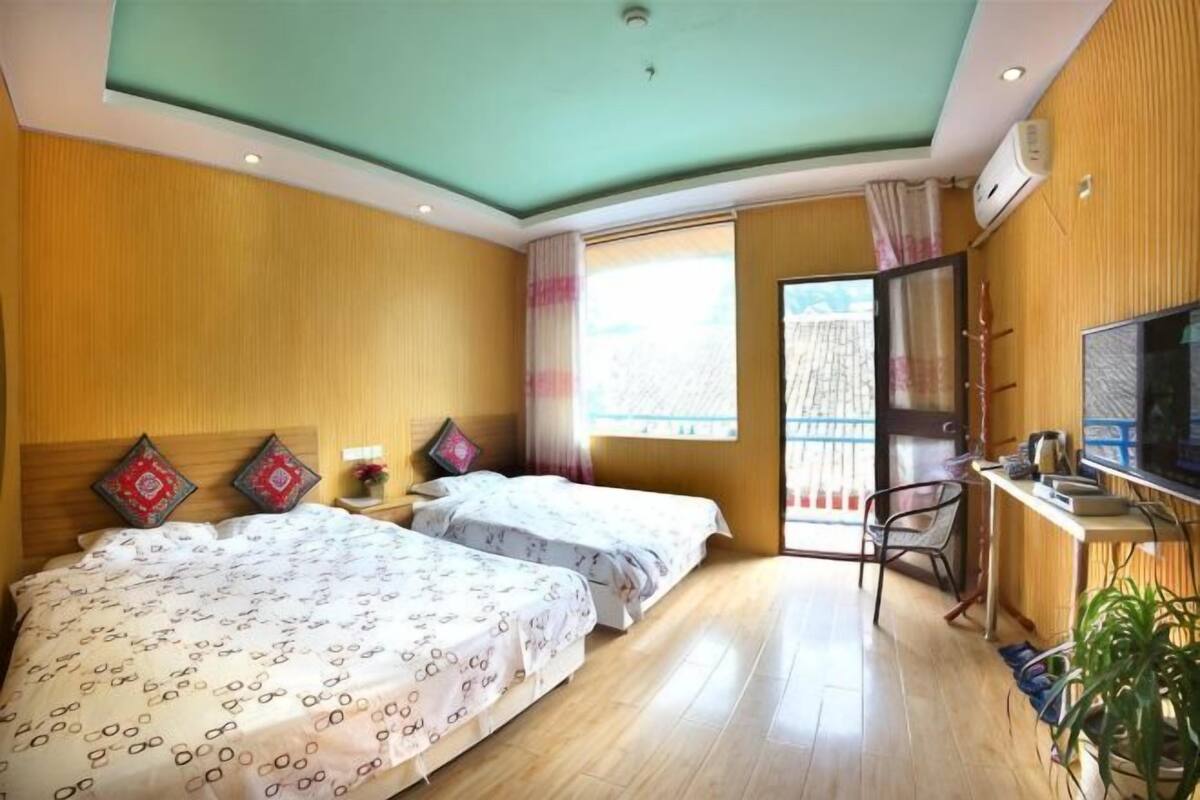 Une chambre d’hôtel avec deux lits, une télévision, un bureau et une fenêtre.