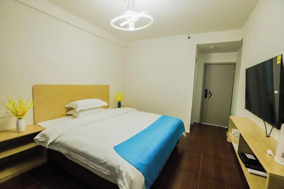Habitació d'hotel amb llit, televisió, escriptori i porta.