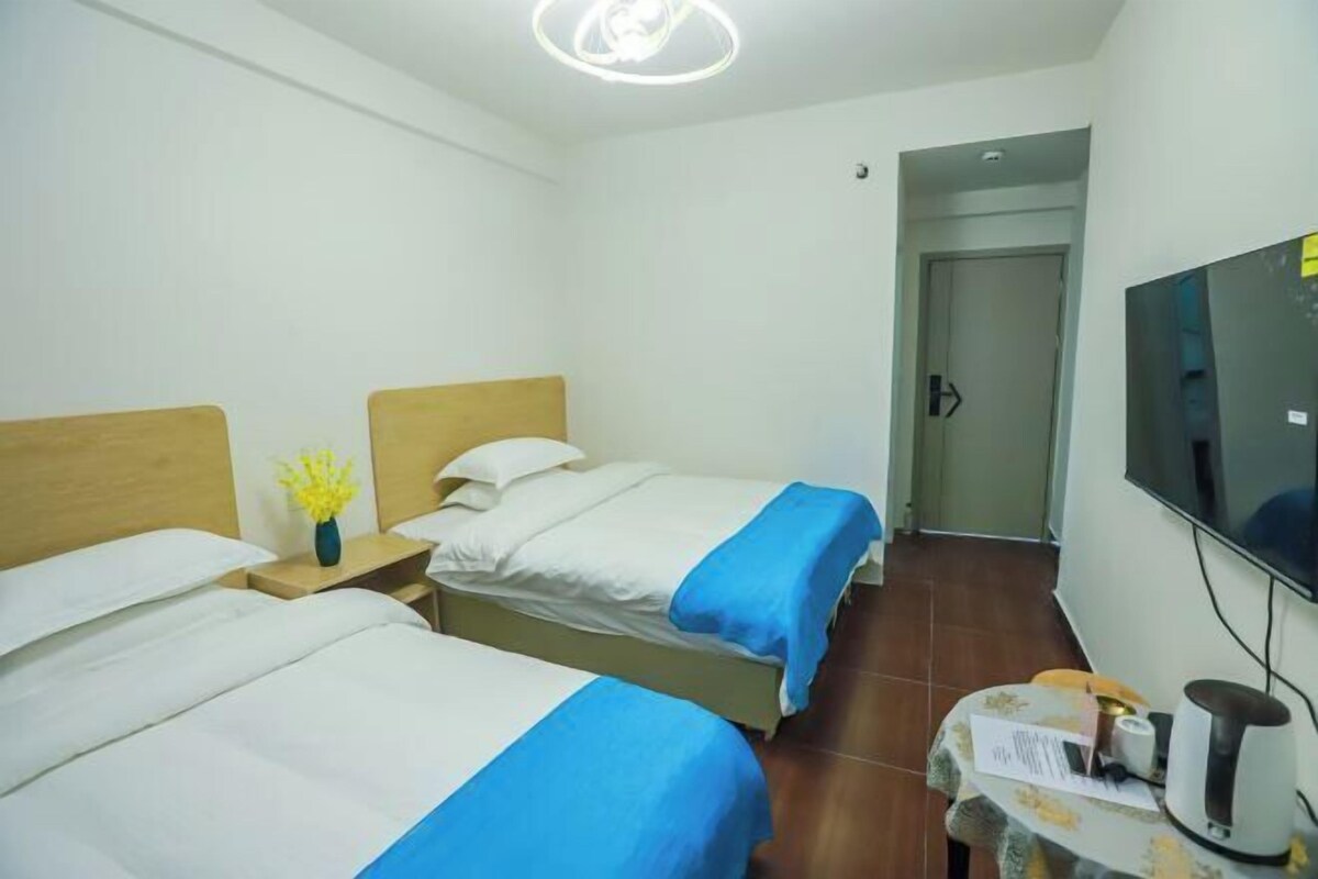 Habitació d'hotel amb dos llits, un televisor, una taula petita amb un búllet i una porta que condueix a una altra habitació.