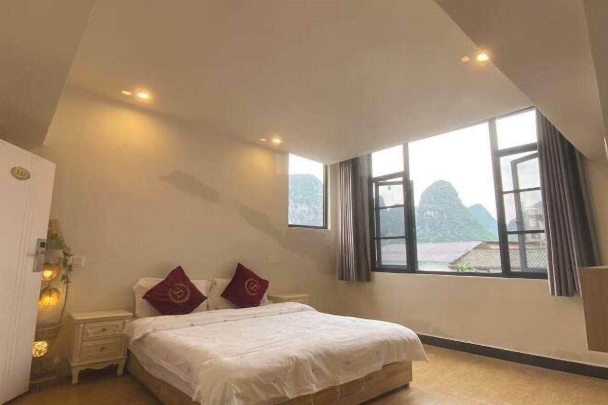 Une chambre à coucher avec un lit, deux oreillers, une table de chevet et une fenêtre donnant sur un beau paysage.