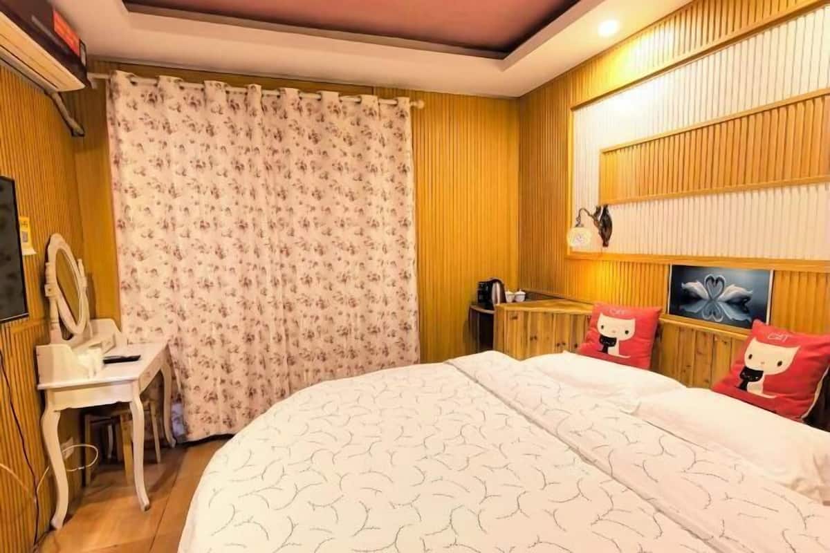 Une chambre à coucher comprenant un lit, un bureau, une chaise, une coiffeuse et un rideau de douche.