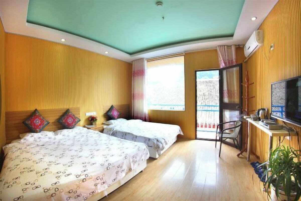 Une chambre d’hôtel avec deux lits, une télévision, un bureau et une fenêtre donnant sur un paysage agréable.