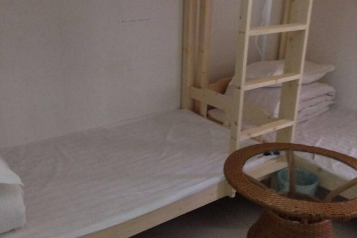 Ein Etagenbett mit einer Stehle, ein kleiner Tisch mit einem Korb und eine zusammengeklappte Decke auf der unteren Schlafstelle.