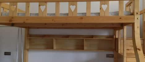 Una cama litera con estructura de madera y cabecera con detalles de corazones.