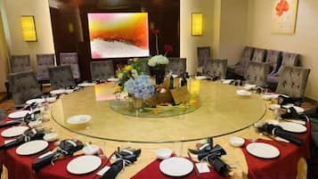 A conference room with a round table, chairs, and a large screen.