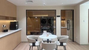 A modern kitchen with a round dining table and four chairs, a built-in oven, and a refrigerator. - Yonghaoyuan Hotel (Luoding)