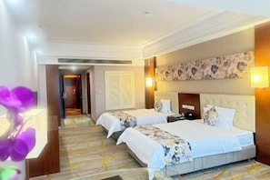 Quarto de hotel com duas camas, uma grande obra de arte floral na parede e design moderno.