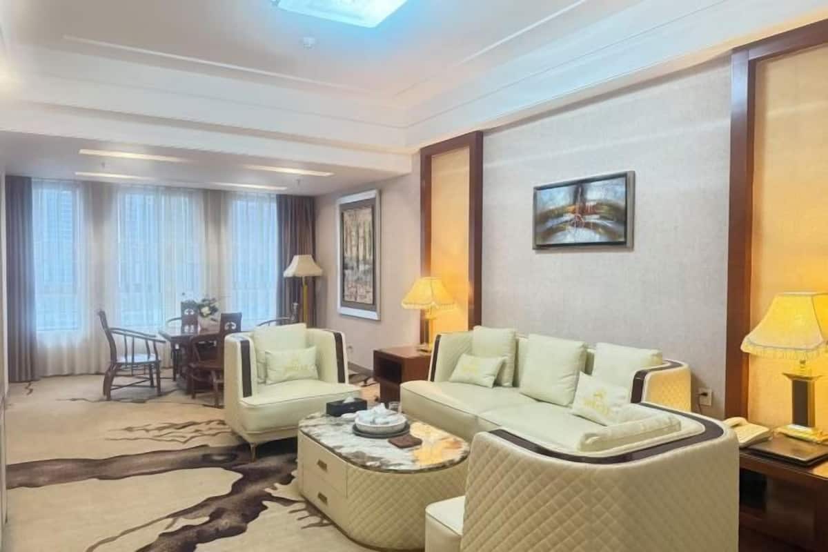 Une chambre d’hôtel comprenant un canapé, une table à manger avec des chaises, une table basse et un tableau au mur.
