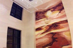 Un techo alto con una lámpara geométrica y un gran mural abstracto en la pared.
