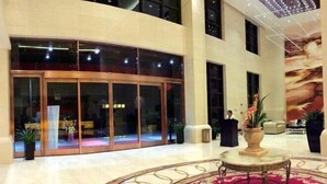 A hotel lobby with a glass entrance, a round table, and a large mural on the wall. - Yonghaoyuan Hotel (Luoding)