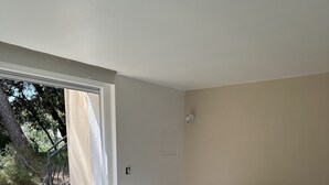 A bedroom with a bed, pillows, a round rug, and a view of the outdoors. - Pleasant house in a quiet area, swimming pool, air conditioning, WIFI, max 12 pers. (Uchaux)