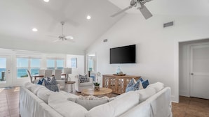 A spacious living room with a white sofa, a coffee table, and a TV mounted on the wall.