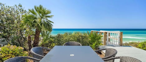 Une terrasse en bord de mer, avec une table et des chaises en osier, donnant sur l’océan.