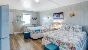 Una camera da letto con due letti, una ventola a soffitto, una finestra e una parete con un quadro.