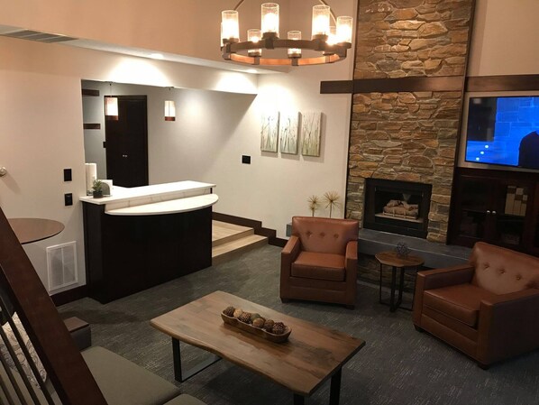 A modern living room with a stone fireplace, a reception desk, and a television.