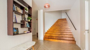 A staircase with wooden steps, a bench, and a bookshelf with books and decorative items.