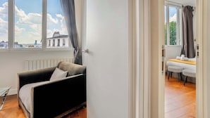 Une pièce avec un canapé, une petite table et une vue sur les immeubles par la fenêtre.