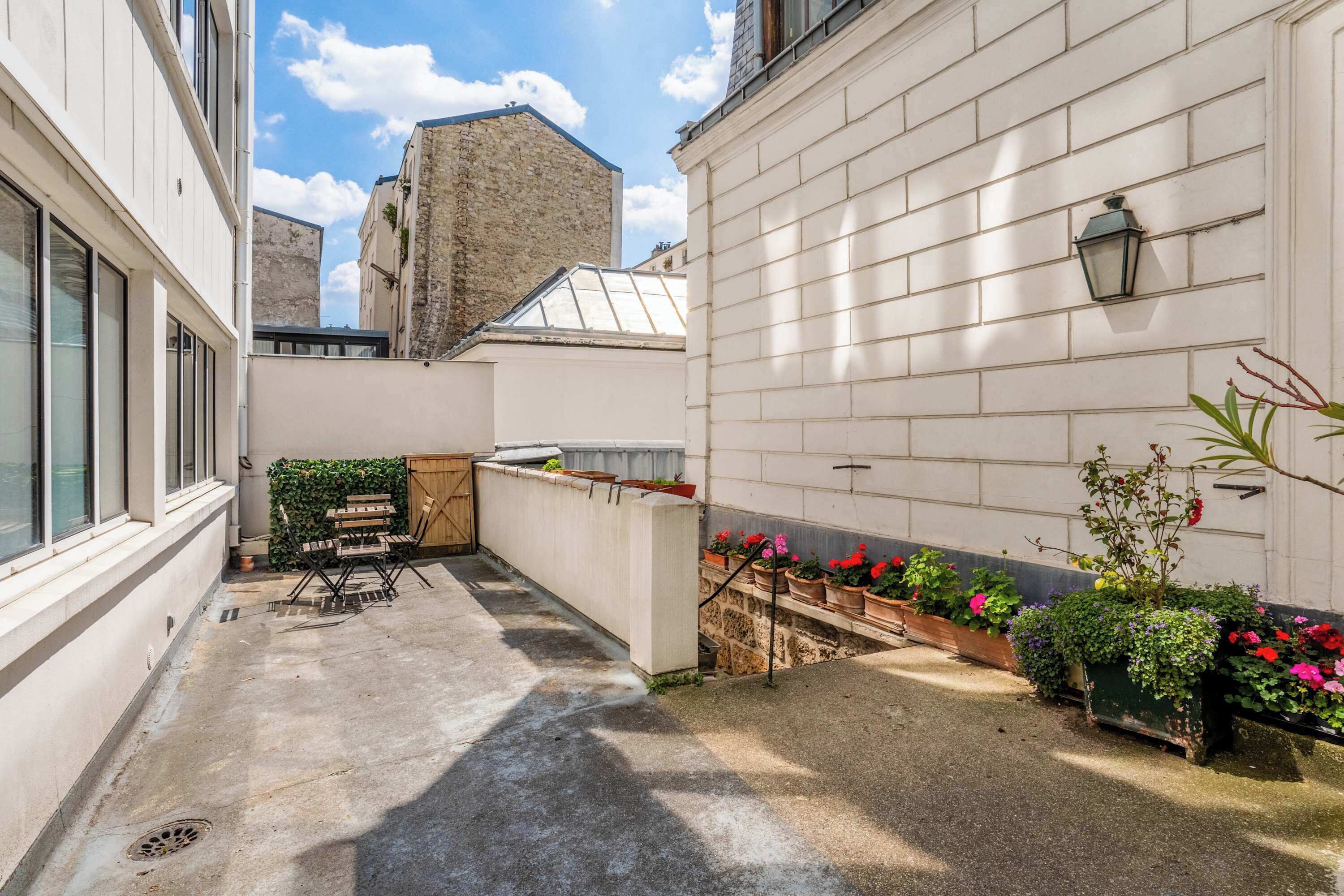 A courtyard with a seating area, potted plants, and a building with a stone facade.