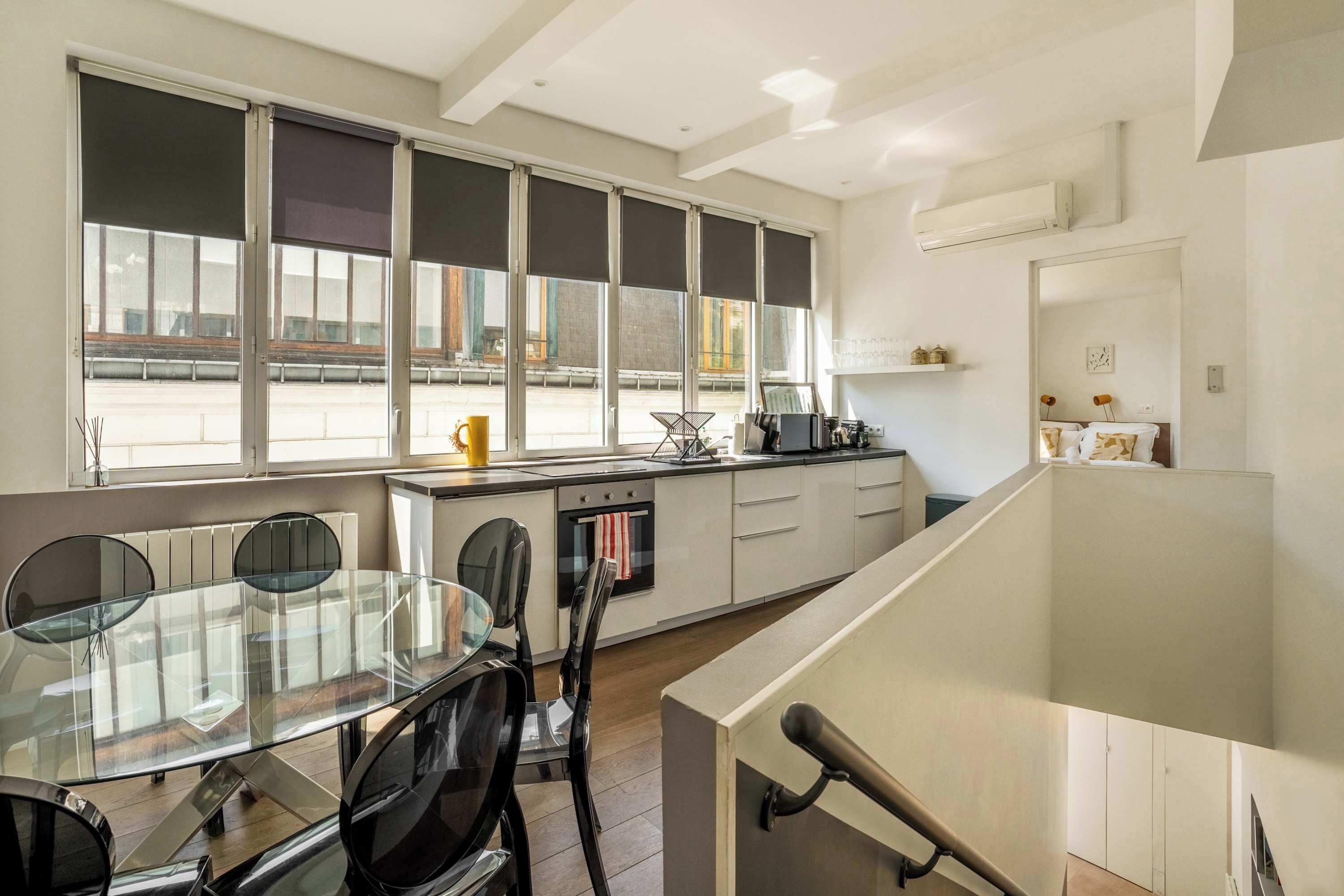 Una cucina moderna con zona pranzo, ampie finestre e vista esterna.