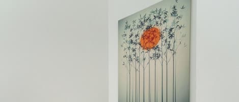 Ein Badezimmer mit Toilette, einem wandmontierten Lichtschalter und einem gerahmten Kunstwerk darüber.
