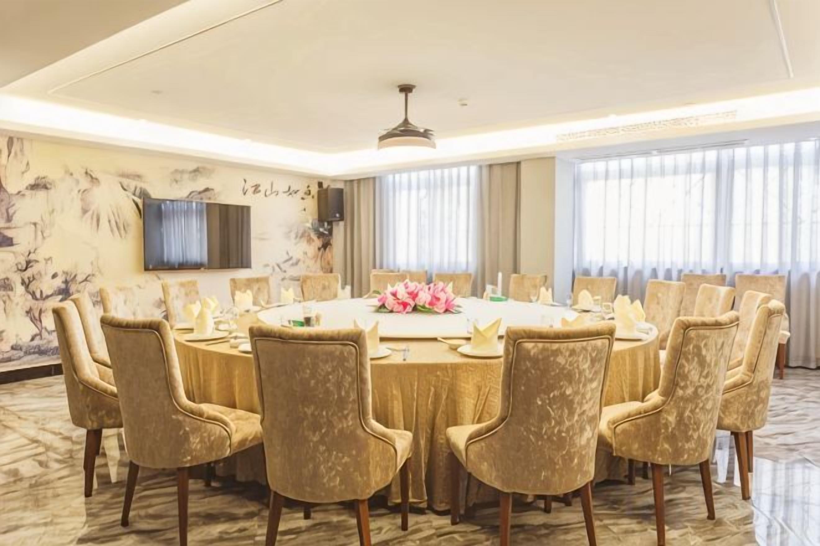 Une salle de conférence équipée d’une table ronde, de chaises et d’un arrangement floral en guise de décoration centrale.