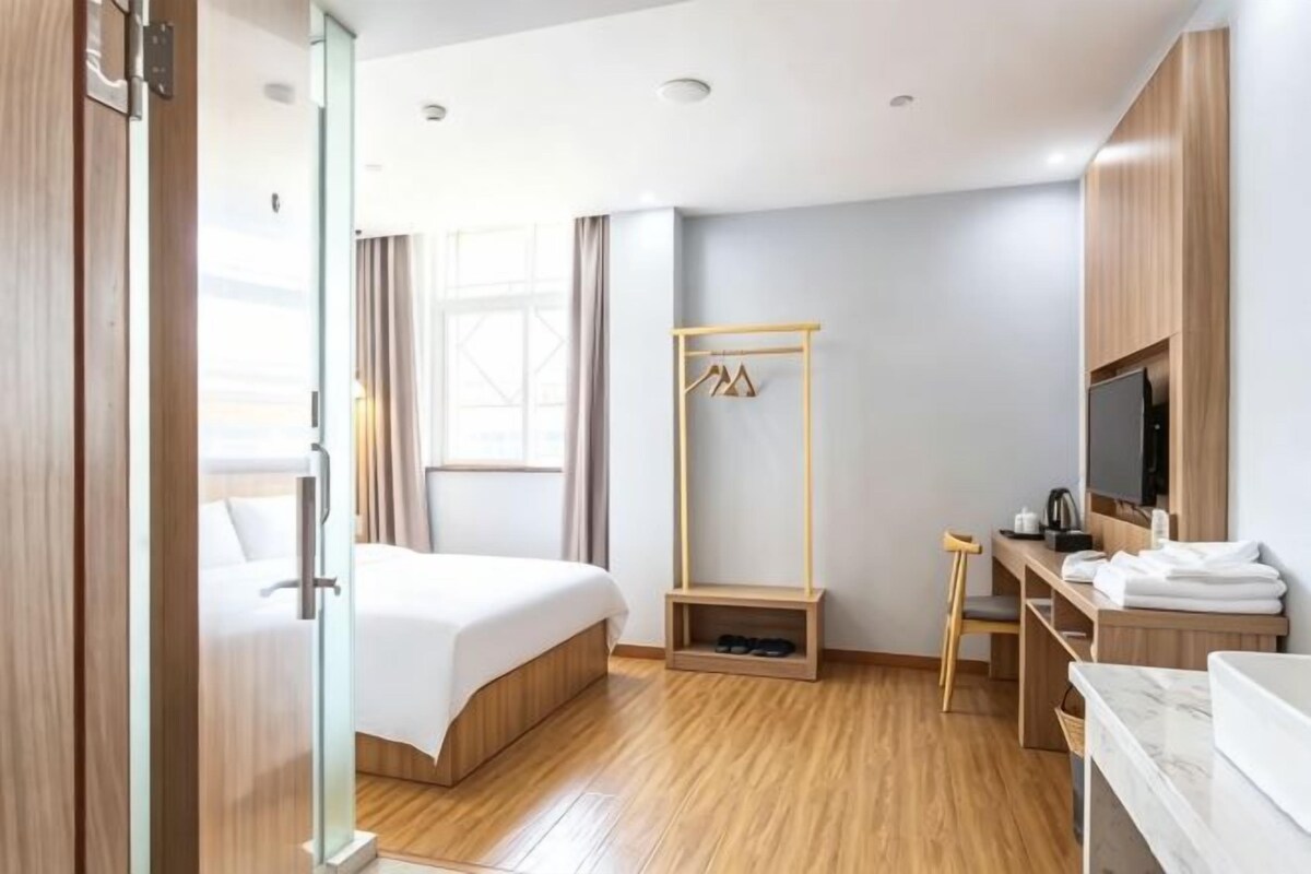 Ein Hotelzimmer mit Bett, Schreibtisch, Fernseher und Kleiderschrank.