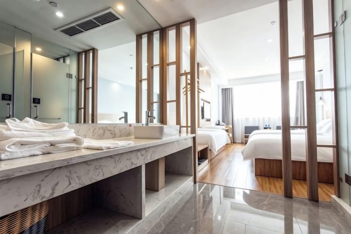 Ein modernes Badezimmer in einem Hotel mit Marmorwaschtisch, einem großen Spiegel und einer separaten Duschkabine.