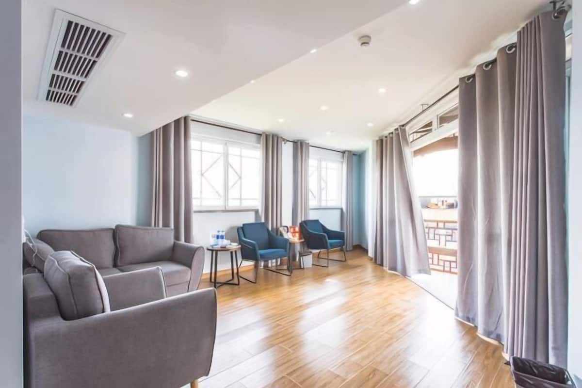 Un salon moderne avec un canapé, des fauteuils, une petite table et de grandes fenêtres.
