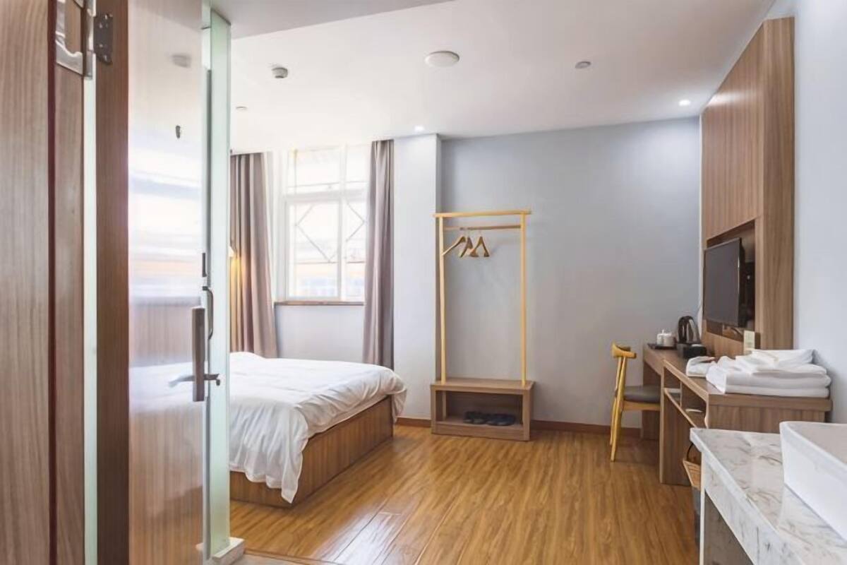 Une chambre d’hôtel équipée d’un lit, d’un bureau, d’une télévision et d’une armoire.
