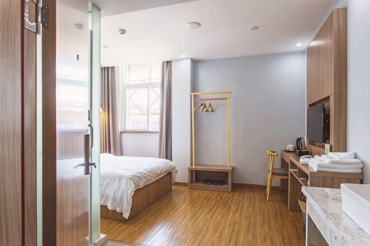 Una habitación de hotel con cama, escritorio, televisor y armario.