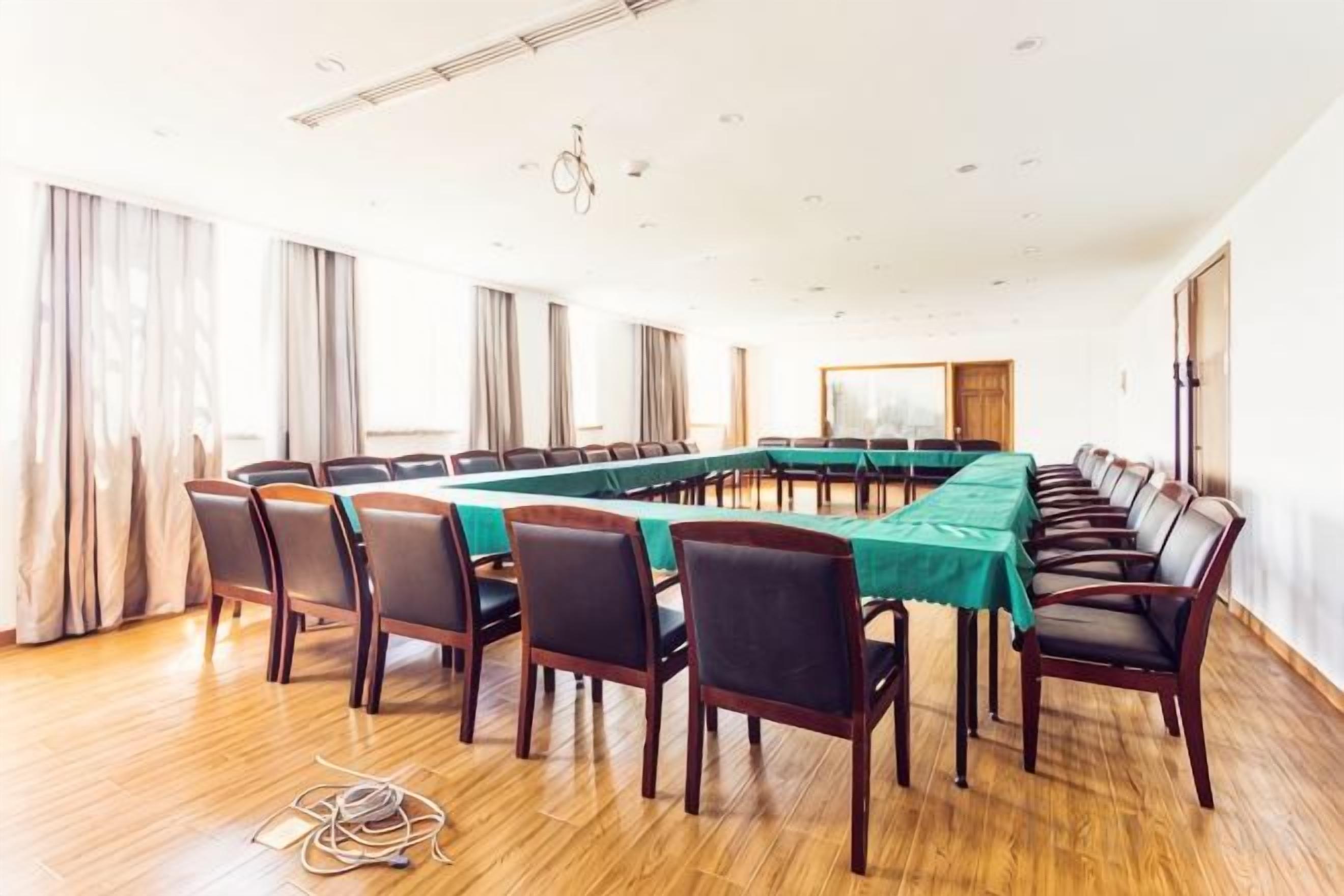 Een vergaderzaal met een lange tafel, stoelen en een projectiescherm.