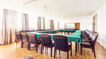 A conference room with a long table, chairs, and a projector screen.