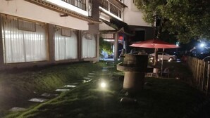 Une cour avec un élément décoratif aquatique, un parasol rouge et un bâtiment doté de grandes fenêtres.