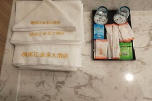 Een handdoek met hotelnaam, een dienblad met flessen en verpakte items.