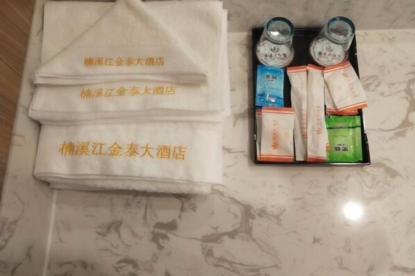 Une serviette portant le nom de l’hôtel, un plateau avec des bouteilles et des articles emballés.