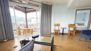 Habitación de hotel con balcón, cama, zona de estar con sillas y una mesita.