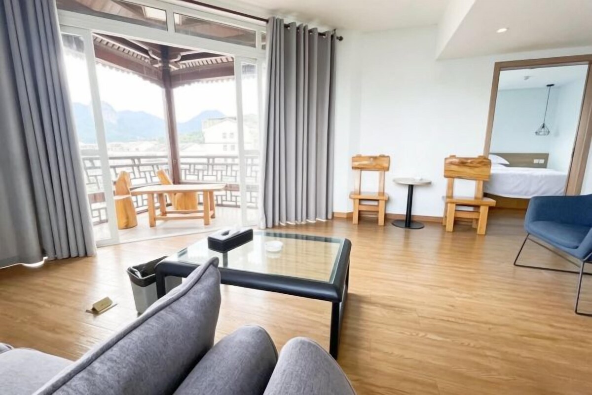 Ein modernes Hotelzimmer mit Balkon, einer Couch, einem kleinen Tisch und einem Bett.