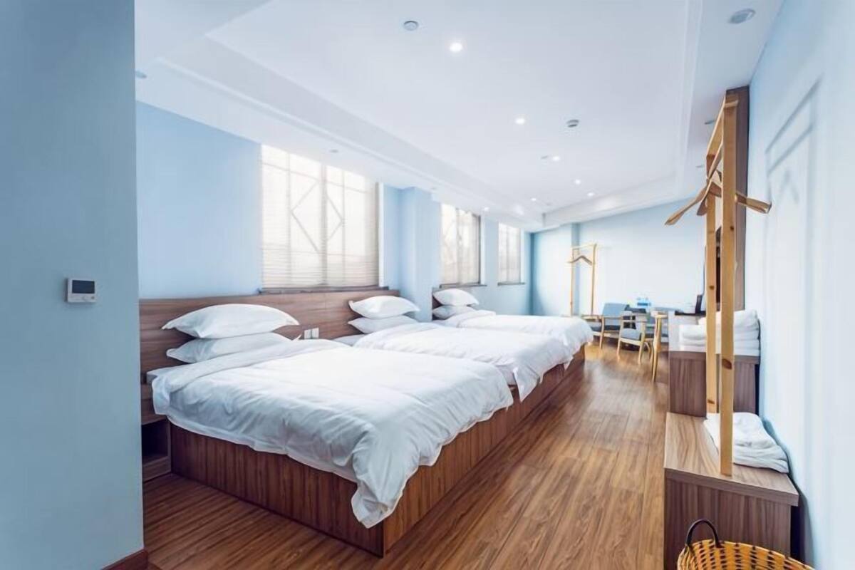 Une chambre d’hôtel avec deux lits, un bureau, une chaise et un grand miroir.